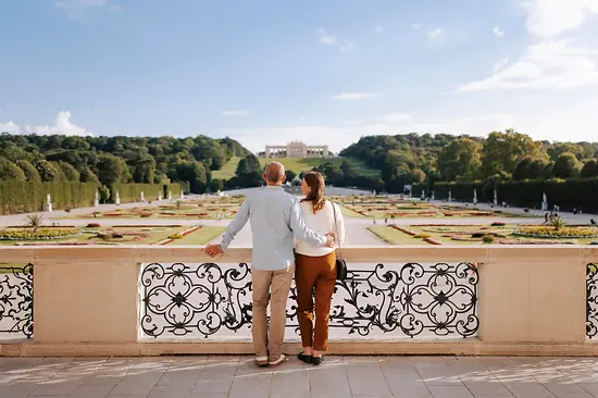 Zwei Personen auf der Terrasse des Schloss Schönbrunn schauen in Richtung Garten und Gloriette
